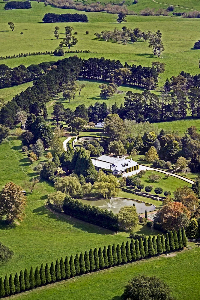 Aerial view of a Southern Highlands country estate with a long row of conifers and blocks of trees sheltering the house garden from the paddocks