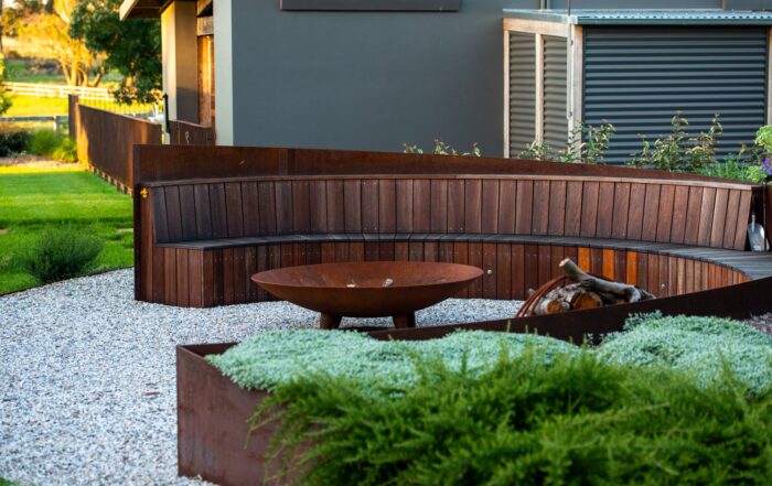 Outdoor living area with fire pit and curved bench by Nicholas Bray Landscapes