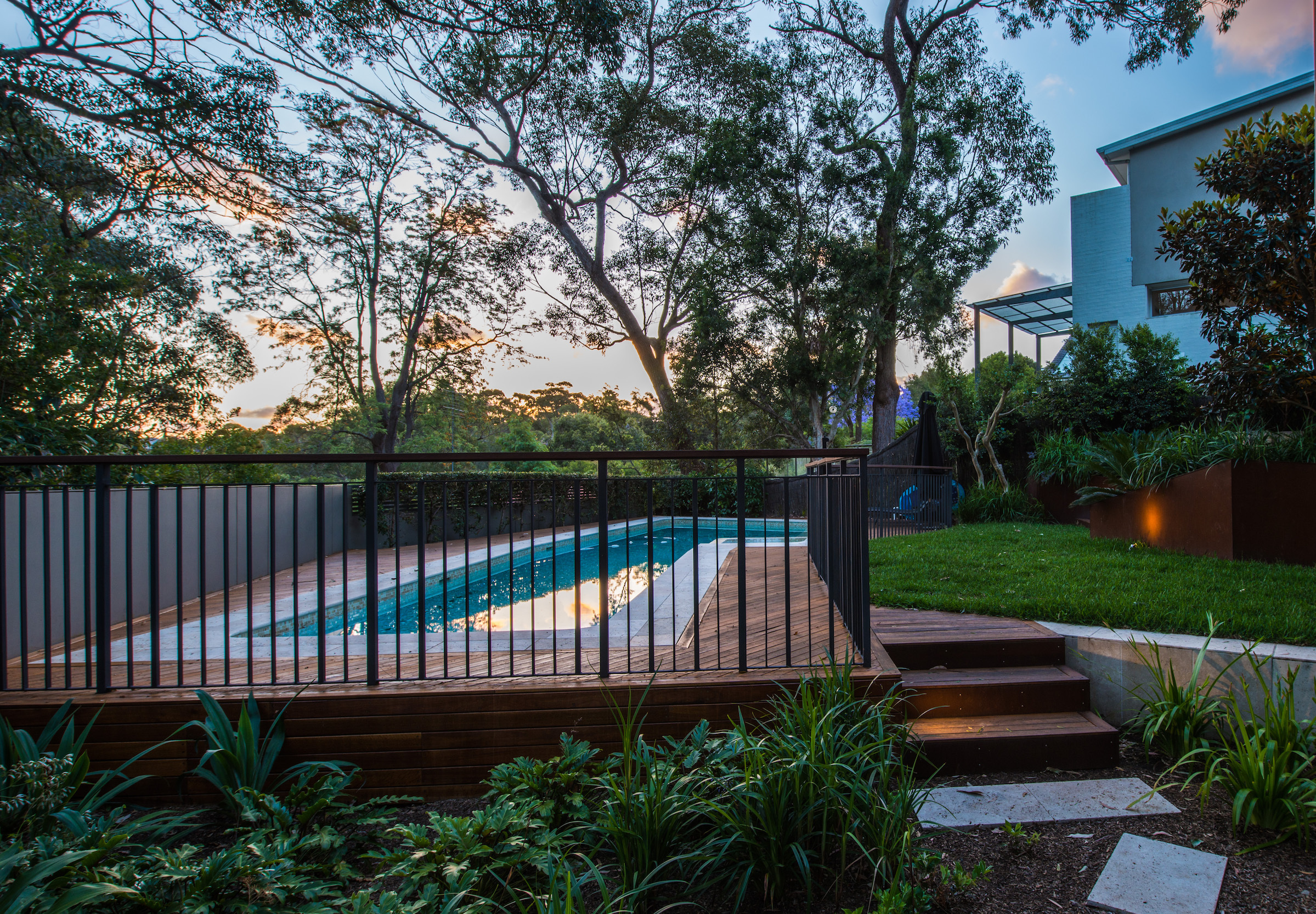 Hero-image1 Swimming pool and garden at dusk behind a dark fence